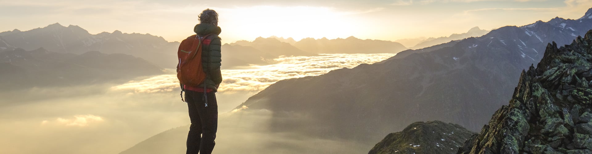 Man standing on top of mountain above the clouds -