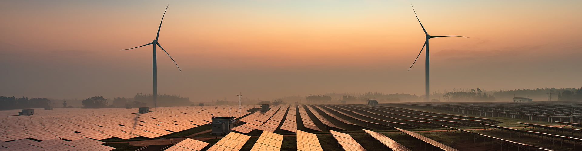 Solar panels and wind turbines against a misty sky